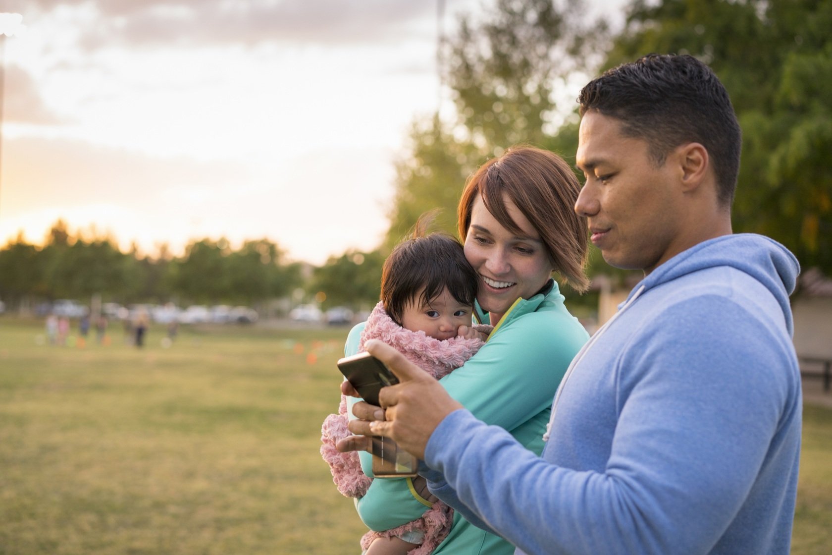 couple-with-baby-using-mobile-phone-in-park-2026-03-25-02-19-24-utc