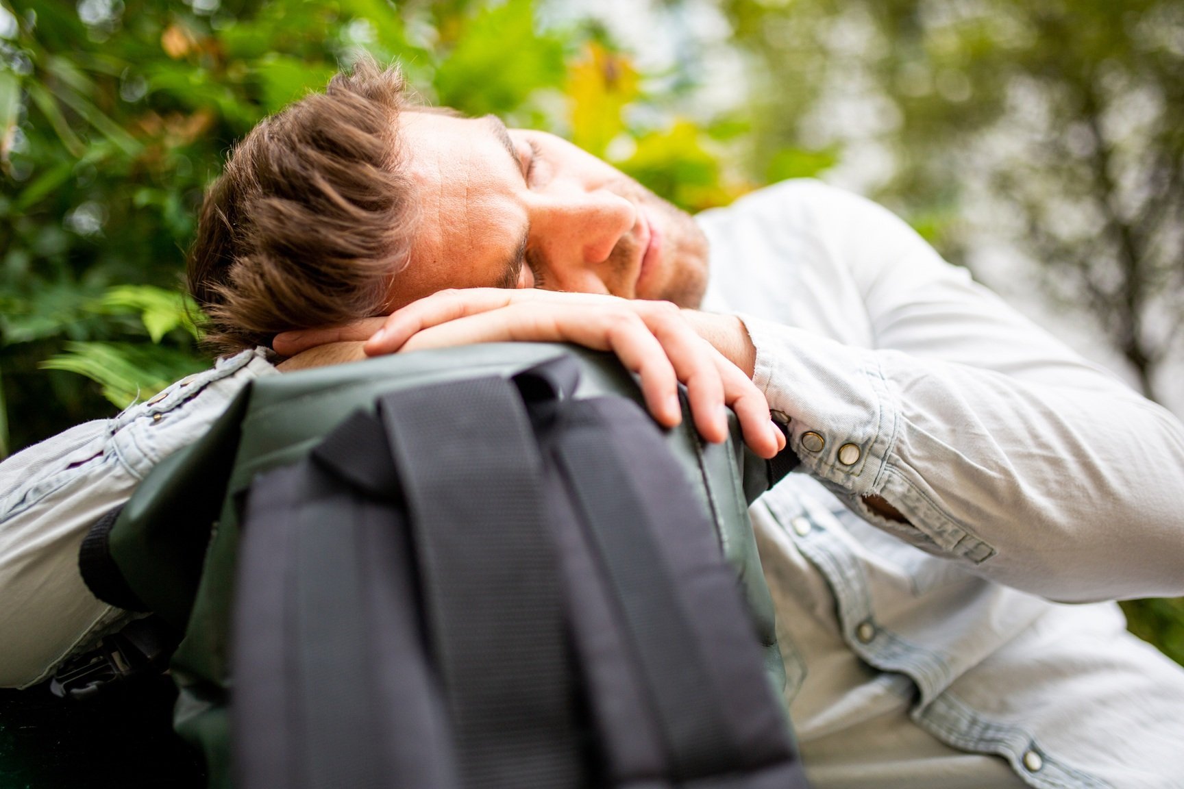 man-resting-head-on-backpack-outdoors-2026-01-05-04-59-10-utc
