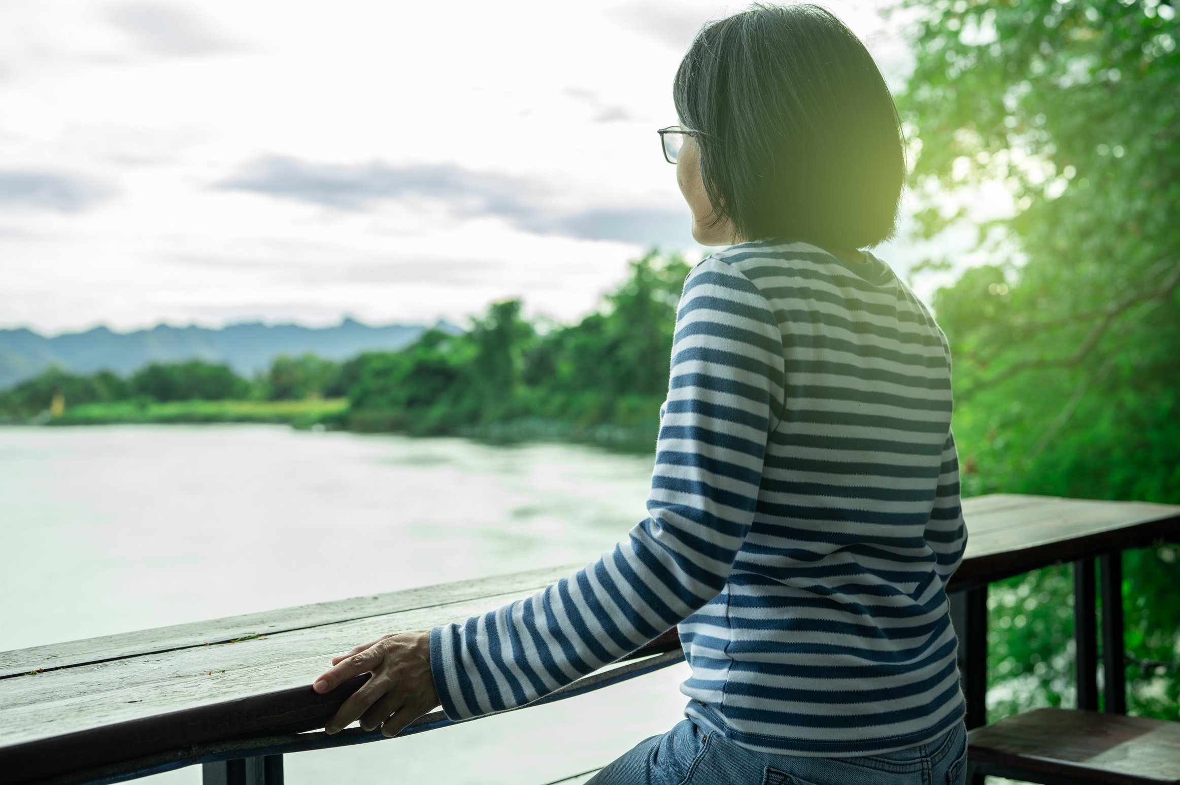rear-view-of-a-woman-gazing-at-calm-river-travel-2026-03-25-04-33-49-utc