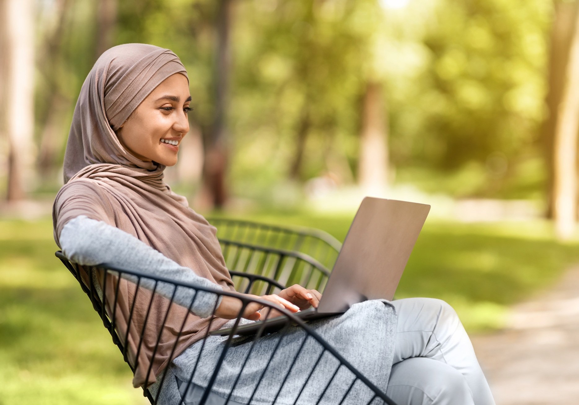 smiling-woman-using-laptop-in-urban-park-2026-01-08-23-13-59-utc