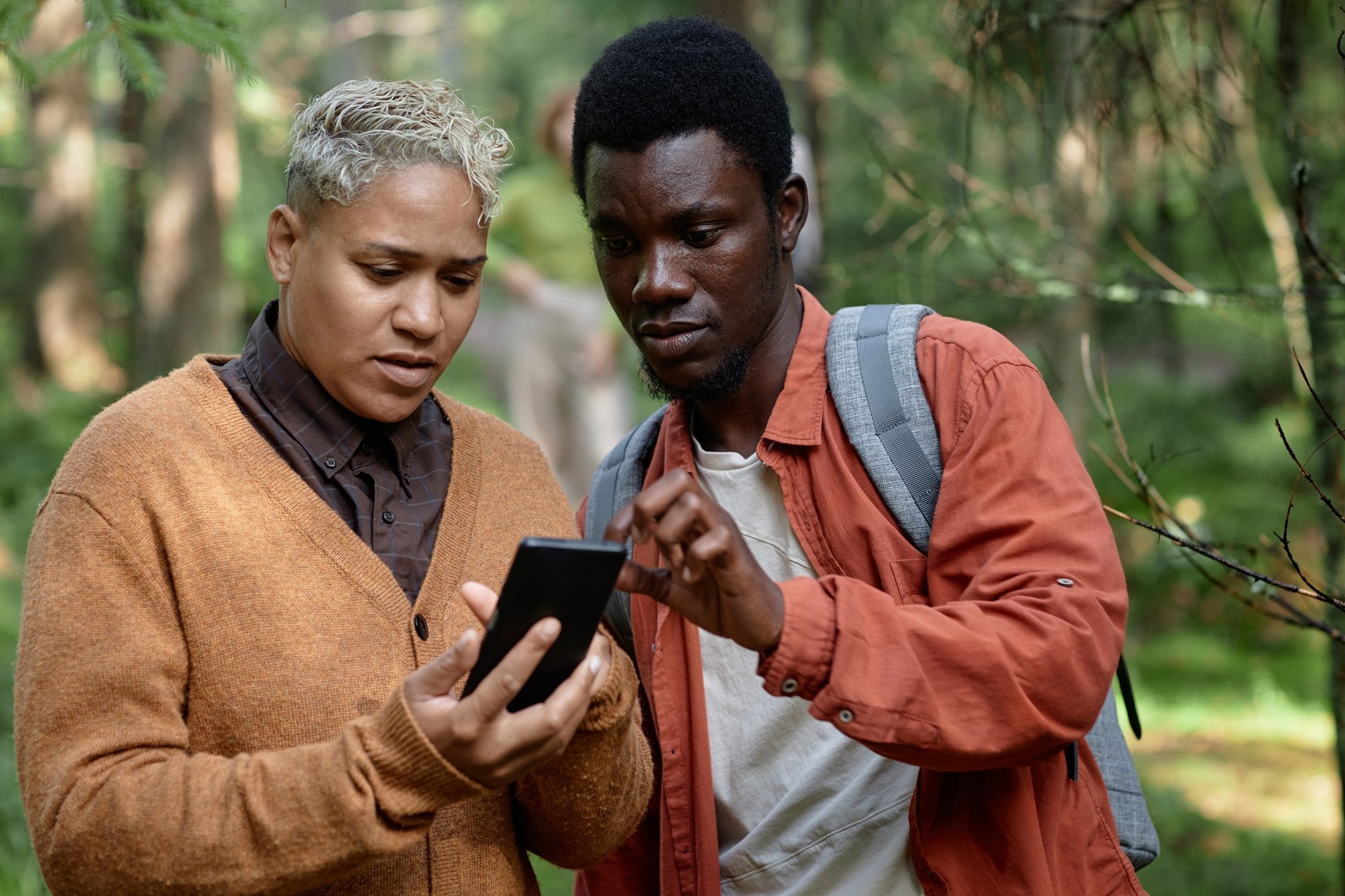 young-couple-using-phone-in-the-forest-2026-03-18-17-42-05-utc